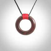 This piece is a fine, zen circle shaped pendant. It was carved from a lovely piece of red jasper stone. It is suspended on an black braided cord that is length adjustable.